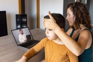 Child experiencing ear pain during a virtual urgent care appointment at home.