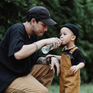 Child drinking water outdoors to prevent dehydration during hot weather.